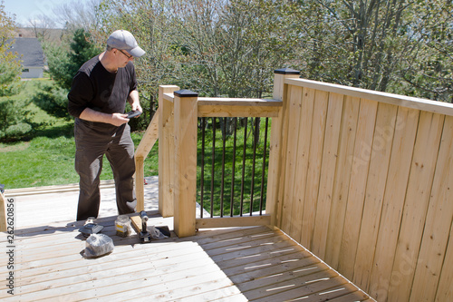  Man works on his deck to put vinyl caps on the top posts photo