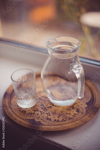 Jug of water and a glass in a tray on the windowsill