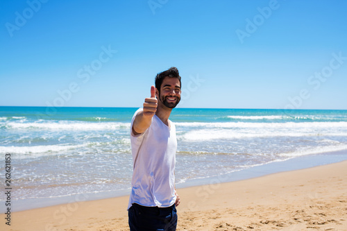 young man doing ok gesture on the beach
