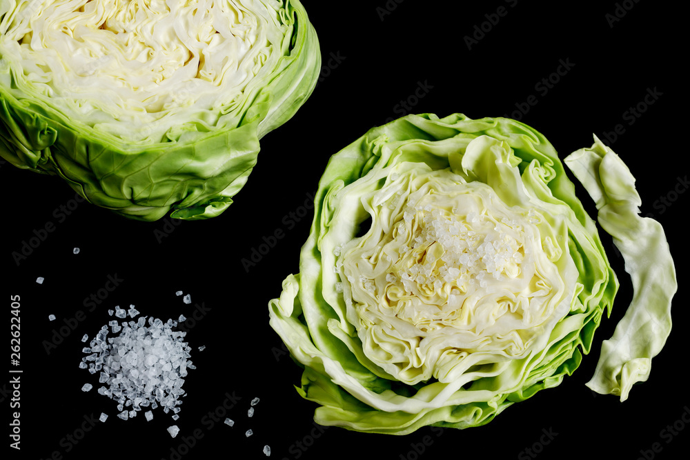 white cabbage slice and coarse sea salt on a black background. white cabbage slice and coarse sea salt on a black background.