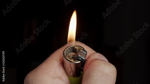 Hand holding green lighter and igniting in slow motion closeup