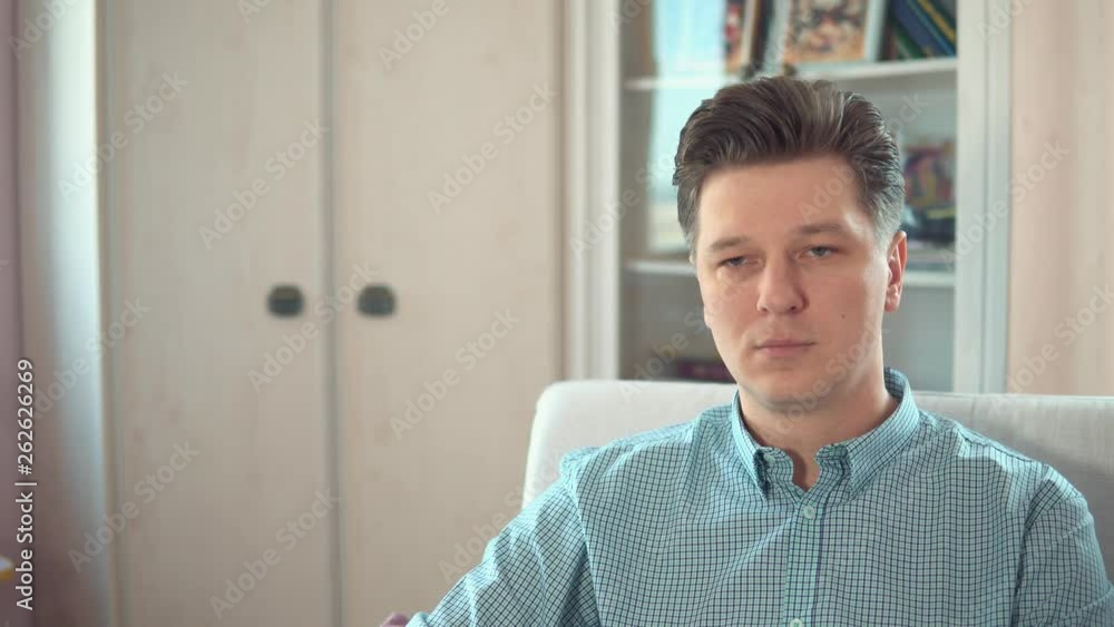 Young sad and tired man sitting at home on the couch Young sad and tired man sitting at home on the couch