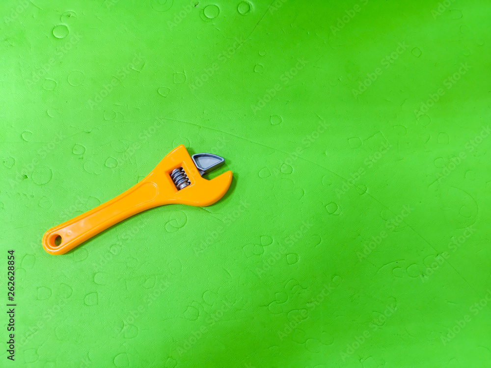Children's wrench on a green background. The tool for the child, etsky repairman, development for children, preparing the child for adult life.