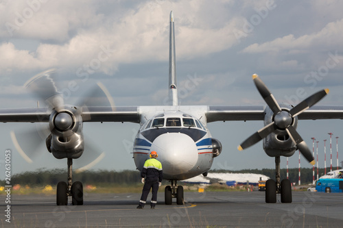 Turboprop aircraft engine check, service before the flight. Maintenance worker standing next to the front of plane, close up. Propeller moving. Aviation,service maintenance concept