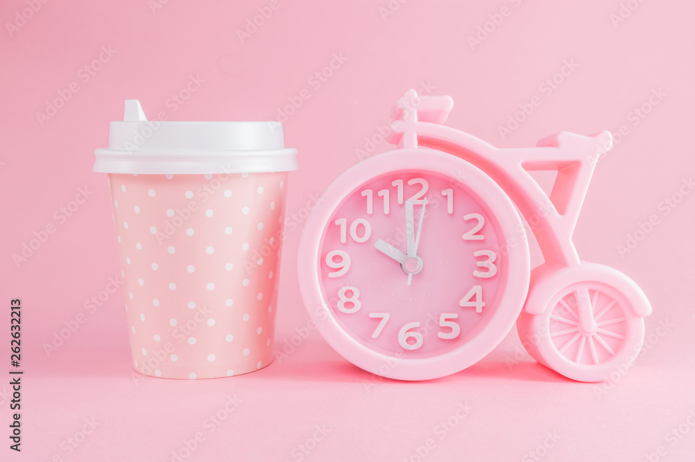 Pink alarm clock and a glass of coffee take-away on a pink background. Coffee time or good morning. Pink alarm clock and a glass of coffee take-away on a pink background. Coffee time or good morning.