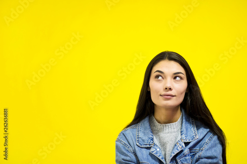 Young beautiful woman looking away at copy space isolated on yellow background. © Betl