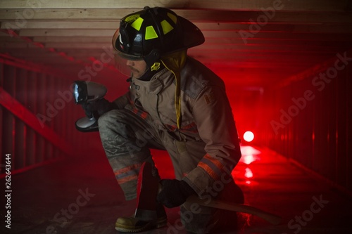 Firefighter in confined spaces looks around with large flashlight