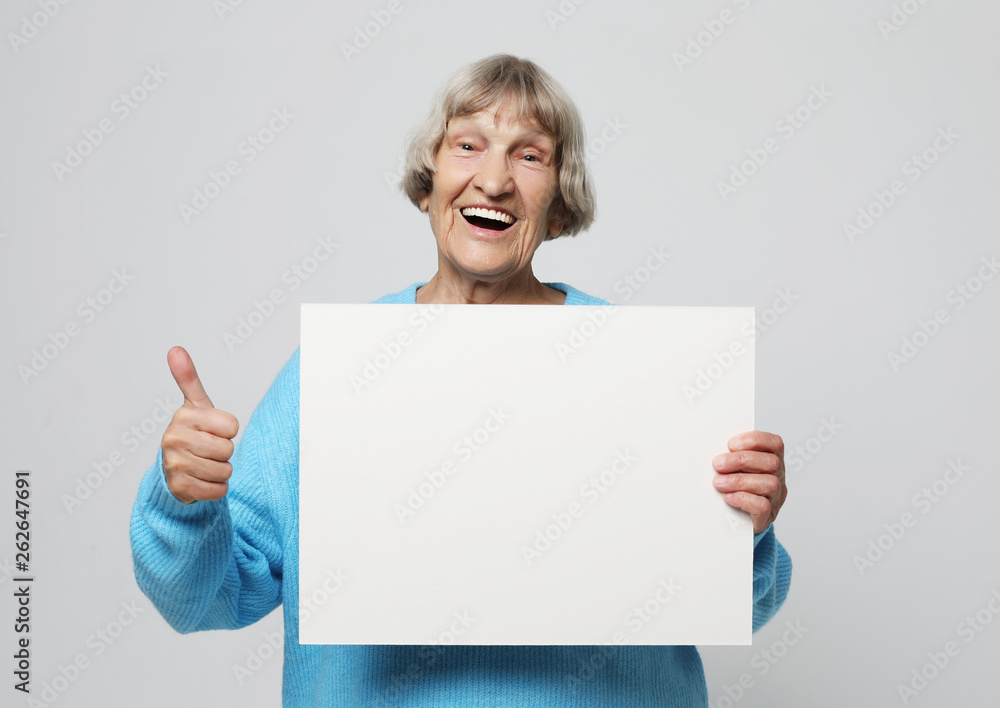 Naklejka premium Aged woman with blank advertising board or copy spacet.