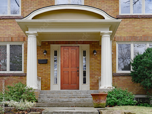 yellow brick house with large portico and wooden front door
