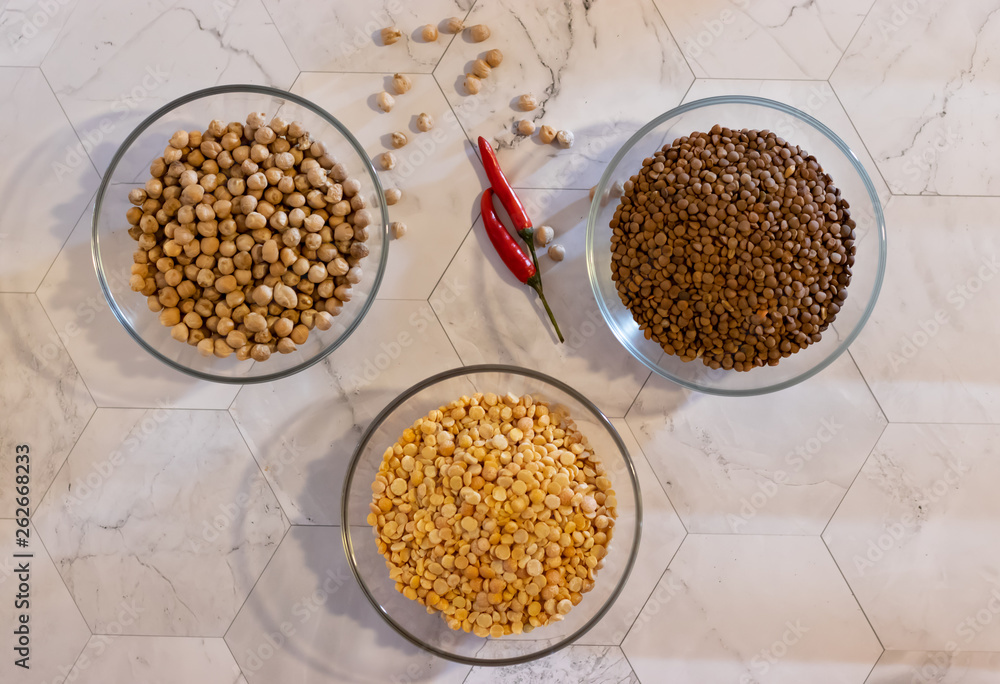 chickpeas lentils and peas in transparent plates with pepper on a light background chickpeas lentils and peas in transparent plates with pepper on a light background