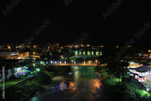 Two bridges crossing over a large tropical river with the reflextion of many colorful lights