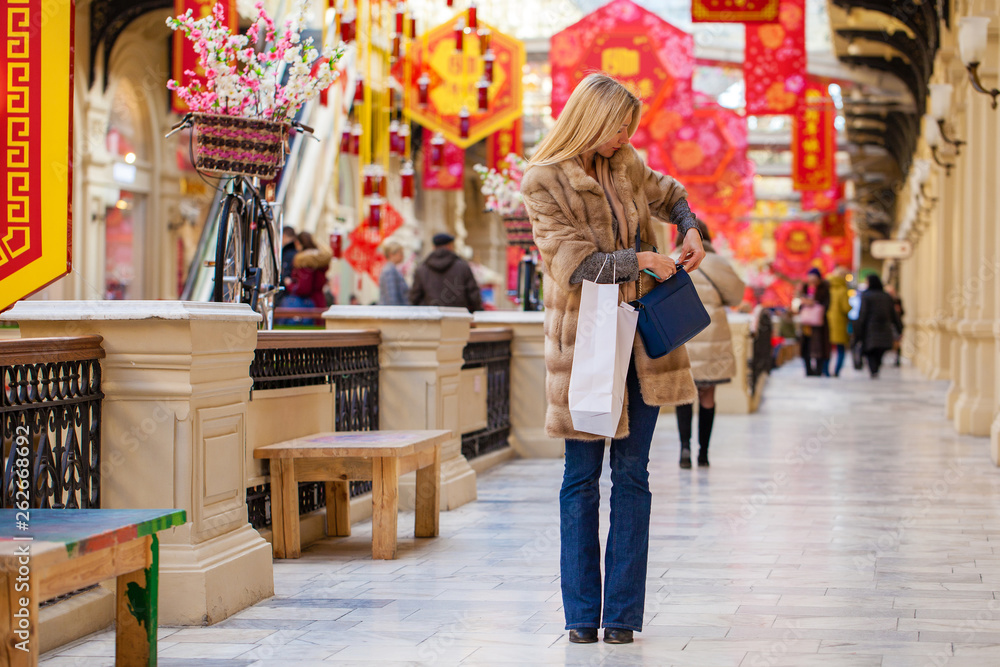 Fototapeta premium Young happy woman with some shopping bags in the mall