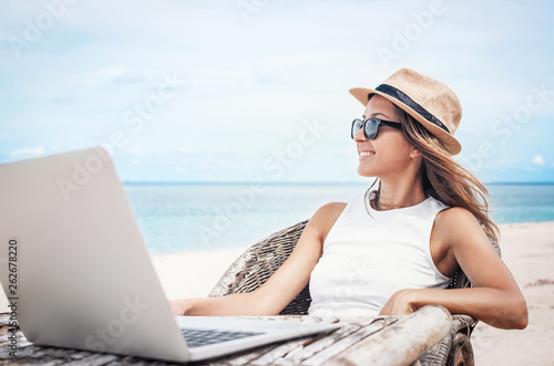 Young woman freelancer working on the beach