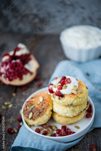 Cheesecakes for Breakfast decorated with pumpkin seeds and pomegranate seeds. Selective focus.
