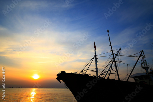 Fototapeta Naklejka Na Ścianę i Meble -  Fishing boats silhouetted against the setting sun
