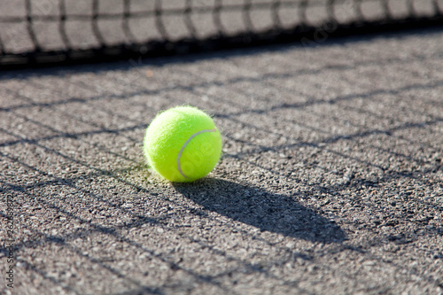 One tennis ball by net on tennis court. Concept of workout, summer sports activities and playing outdoors. © Marina April