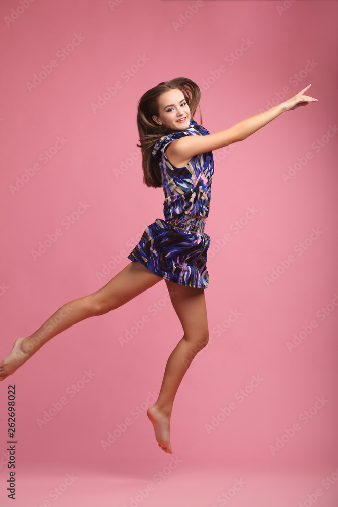 Beautiful, young girl dancer in dress dancing in flight, jumping, happy, smiling, hair evolving, hands in different directions, isolated on pink background, series of photos Beautiful, young girl dancer in dress dancing in flight, jumping, happy, smiling, hair evolving, hands in different directions, isolated on pink background, series of photos