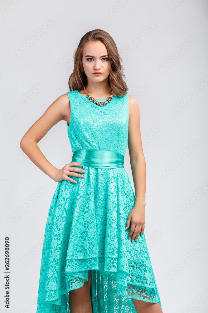 Beautiful young girl in evening turquoise dress, posing, looking at camera