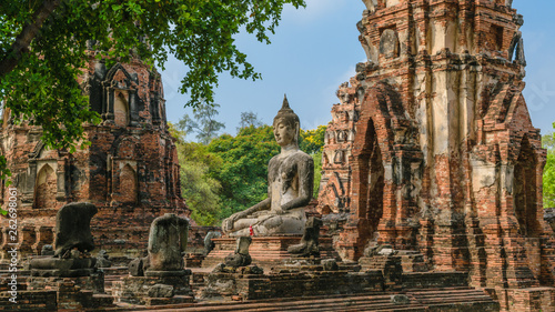 Buddha statue in front of broken pagoda