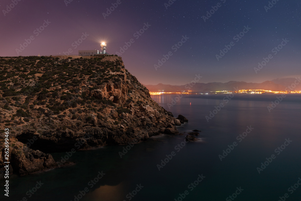 The lighthouse of Mazarron and the bay at night is lit by the light of the full moon
