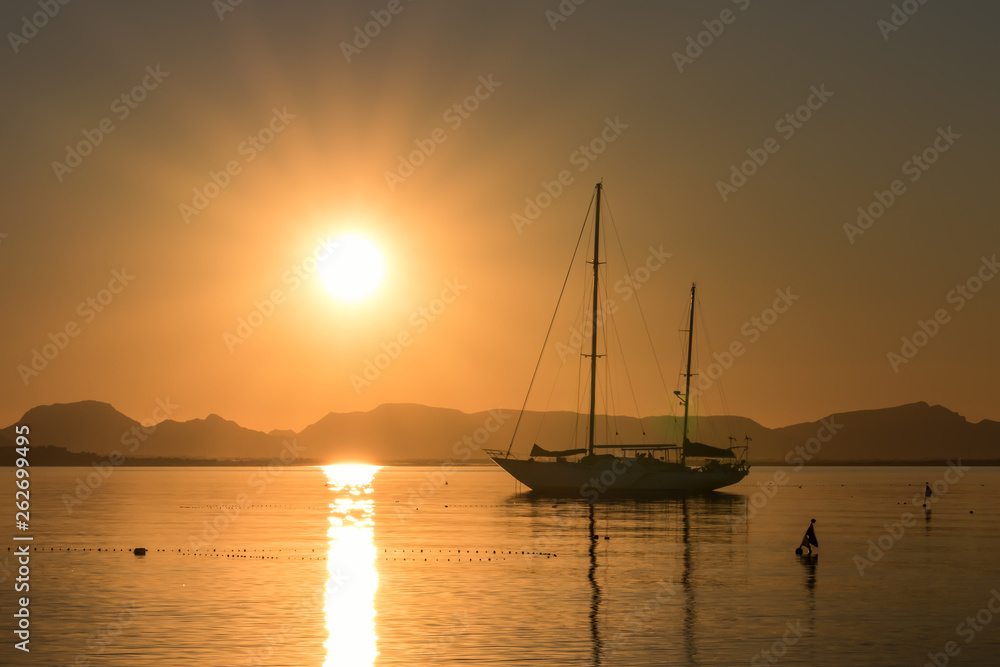A sailboat with two masts anchors at sunset in the Mar Menor in Spain, a very romantic sight