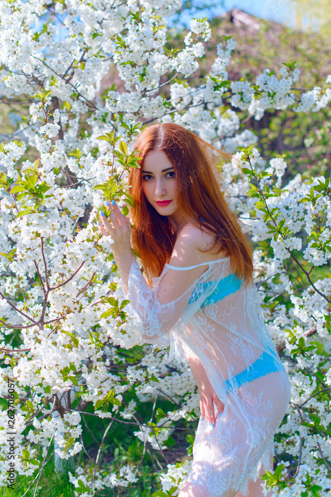 Romantic woman in lace dress at spring blossom garden. Concept of tenderness and modern femininity Romantic woman in lace dress at spring blossom garden. Concept of tenderness and modern femininity