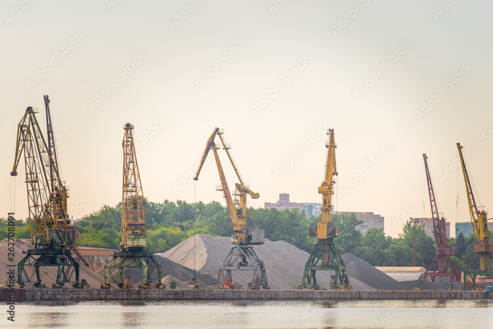 Obraz premium Port loaders and rubble heaps at sunrise