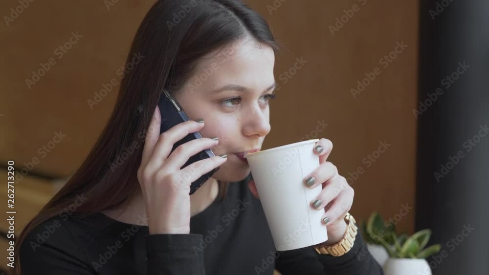 Portrait of a gorgeous girl drinking tasty coffee and talking on the phone in cosy cafe. Close-up view. Portrait of a gorgeous girl drinking tasty coffee and talking on the phone in cosy cafe. Close-up view.