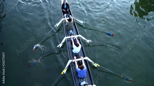 Rowers training on a competition rowing boat in a water canal. View from above.
