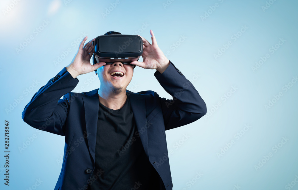 Asian businessman be excited during the view of VR experience with blue background Asian businessman be excited during the view of VR experience with blue background