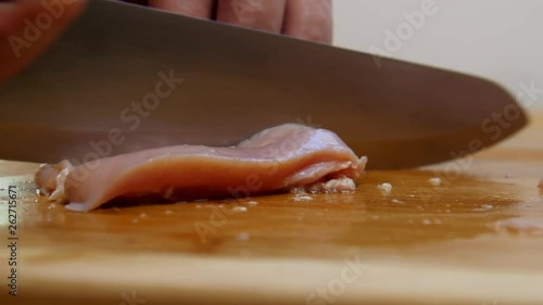 Hand cuts raw chicken into strips. photo