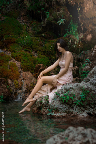 Beautiful girl posing in river. Fairytale story. Natural pool surrounded by green tree's leafs.