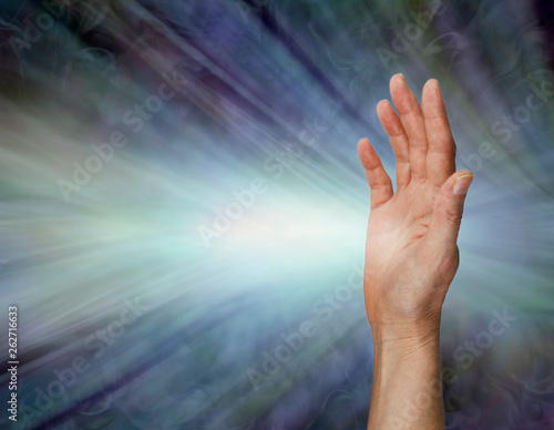 Female Pranic healer sending focused energy from right hand palm chakra -  upright open hand facing out with a stream of white energy flowing horizontally against a blue energy field background with c