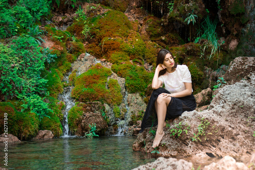 Beautiful dark haired girl posing in river with green plants. Beauty, fashion. Spa, healthcare. Tropical vacation. Natural pool.