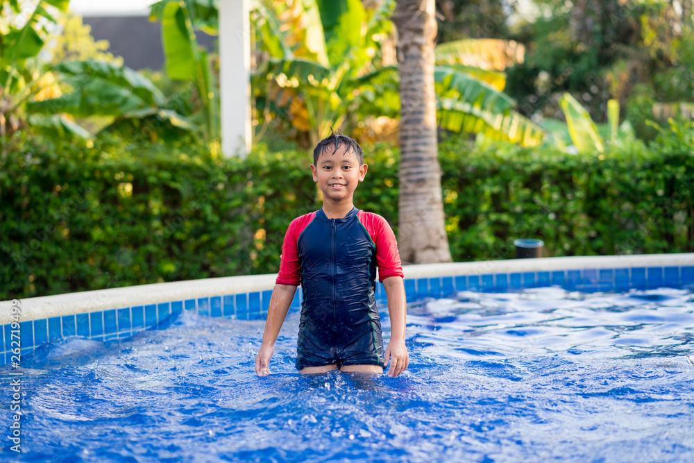 Happy asian kid boy swiming on swiming pool in the summer