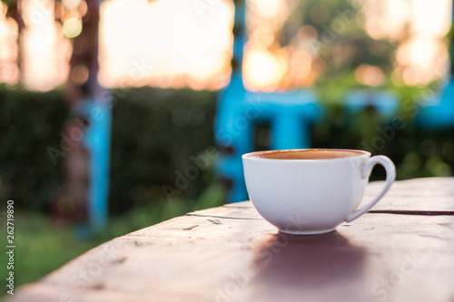 Coffee cup on wooden table at sunset