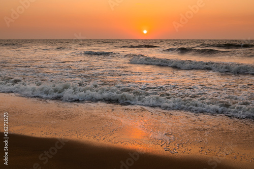 Sea waves on the background of the setting sun. Vacation at sea.