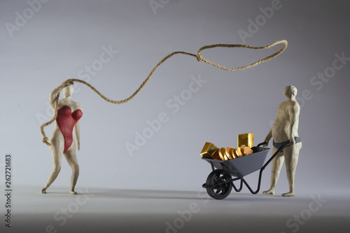 Sexy woman throws a lasso on a rich man.Wheelbarrow filled with gold.  Isolated on grey background. Studio Shot. With space copy text. photo