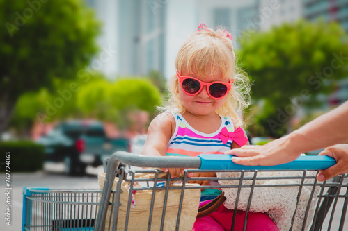 shopping with kids- cute little girl in shopping cart in the city