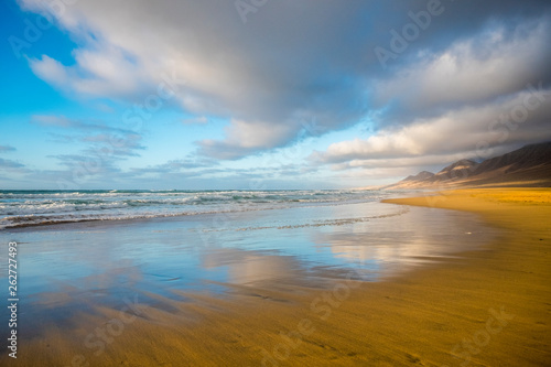 Lonely beach coloured and reflected with beautiful mountain background with cloudy sky - summer tropical vacation concept in free sandy scenic place with nobody there