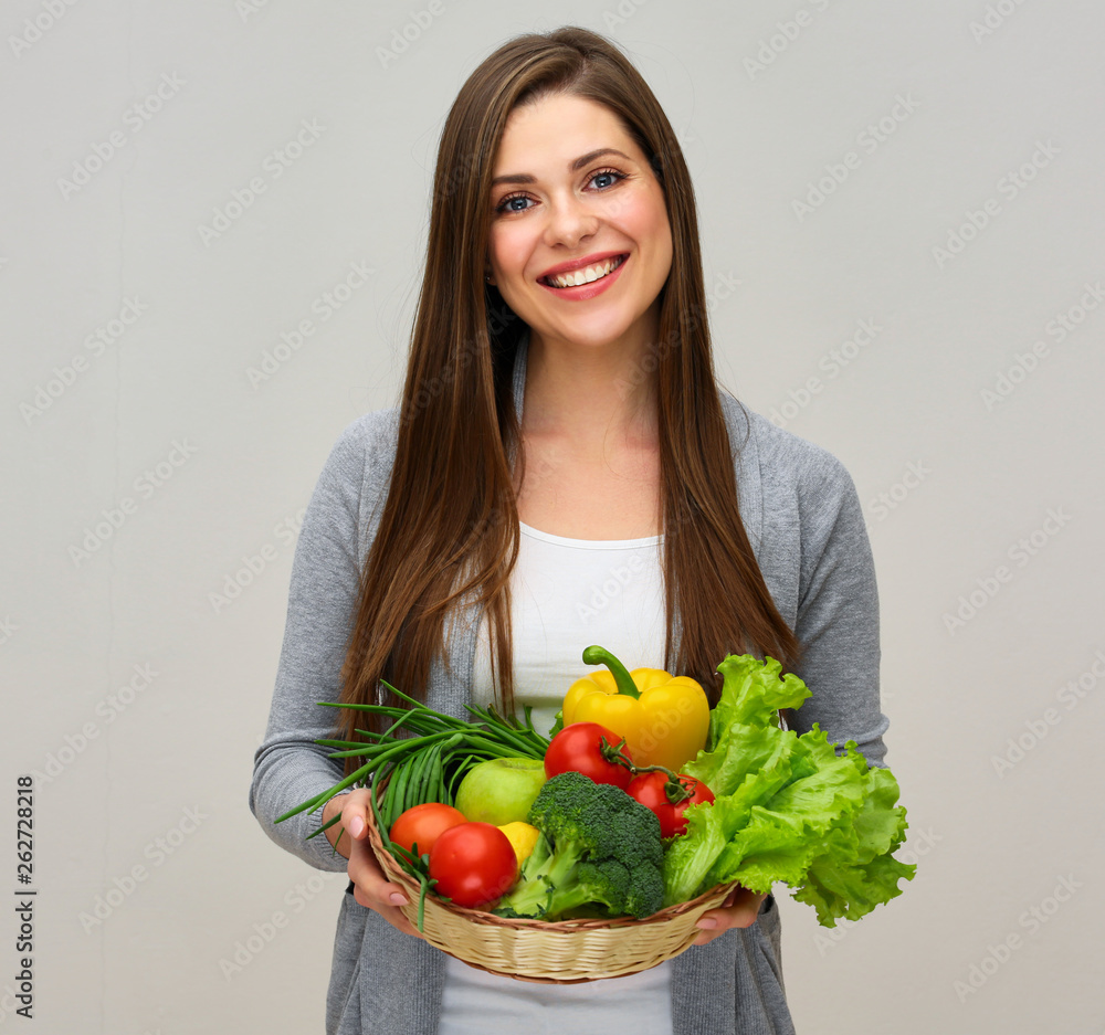smiling woman holding vegetarian food in straw basket smiling woman holding vegetarian food in straw basket