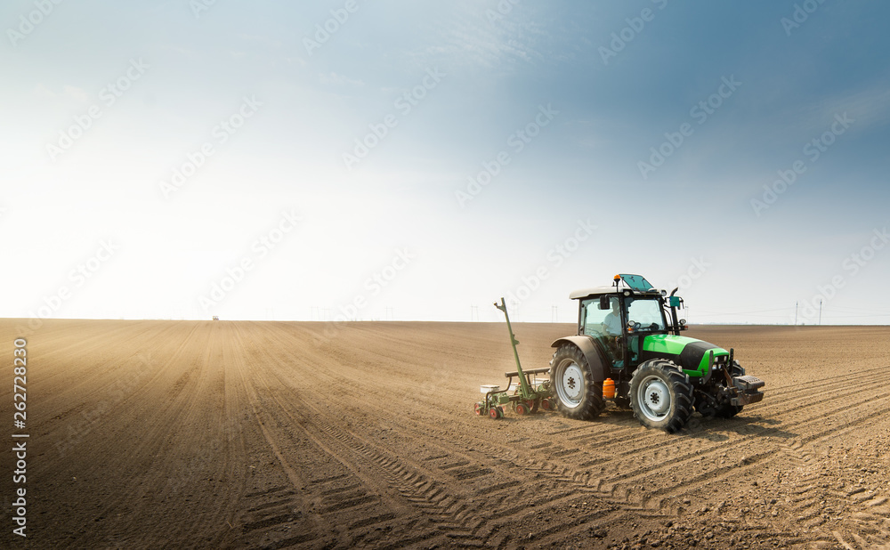 Obraz premium Farmer with tractor seeding sowing crops at agricultural field