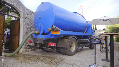 Blue tank truck parked in front of house