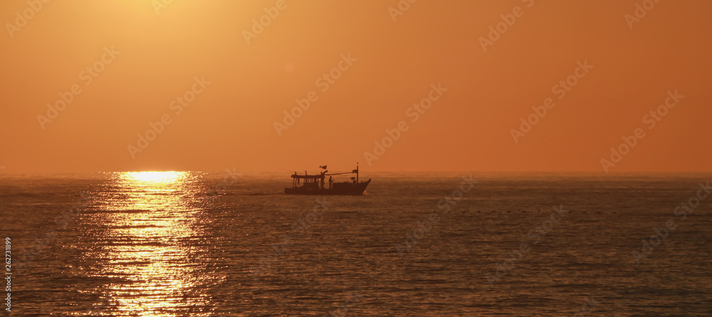 The fisherman's boat is sailing in the sea at sunset.