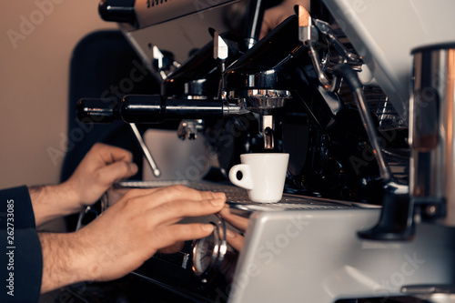Waiter making coffee  with coffee machine and white demitasse