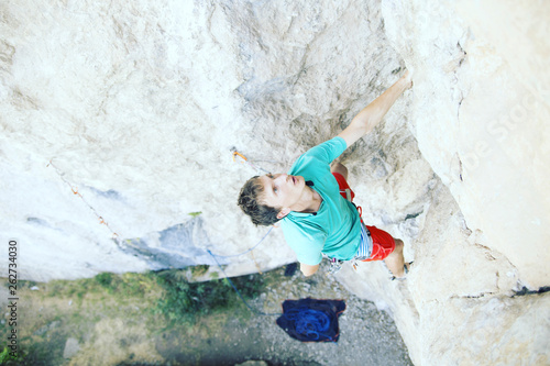 Man rock climber. Rock climber climbs on a rocky wall. Man makes hard move. © vetal1983