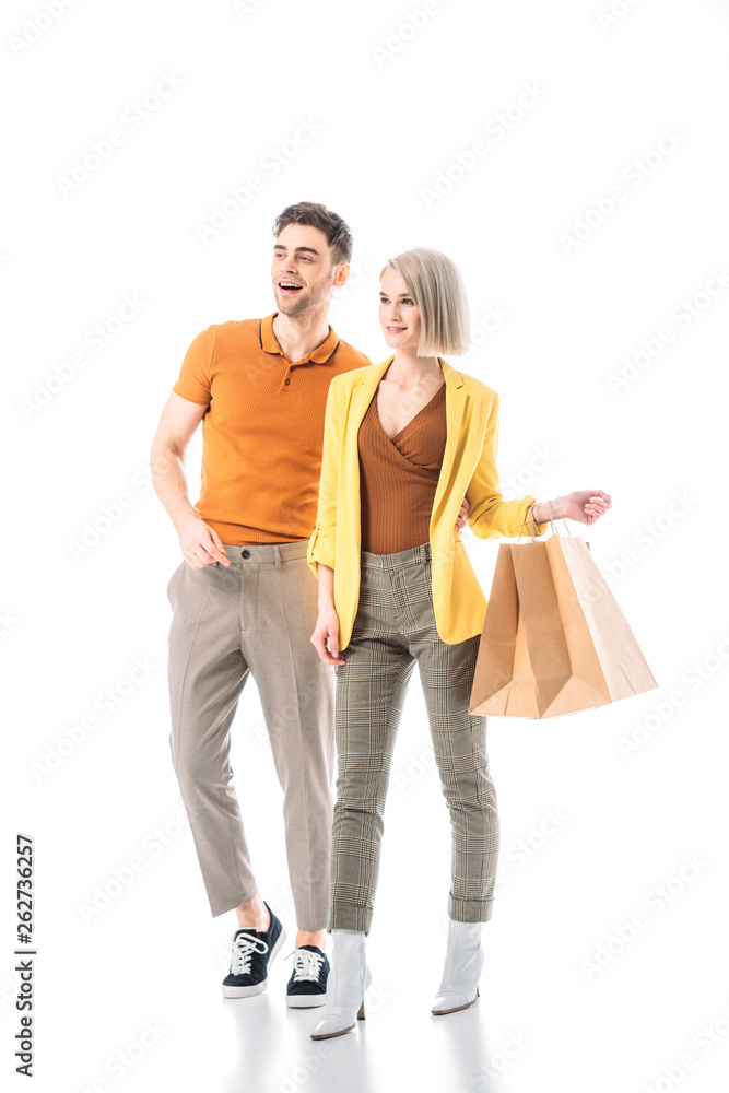 pretty woman holding shopping paper bags while standing near handsome man isolated on white
