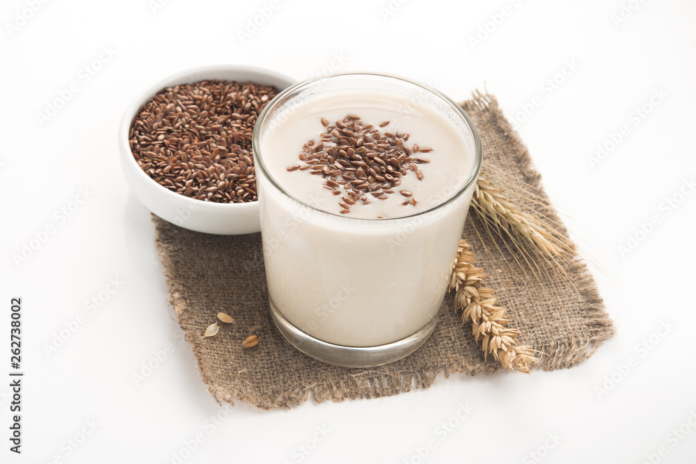 Oat milk in a glass dusted with flax grains Oat milk in a glass dusted with flax grains