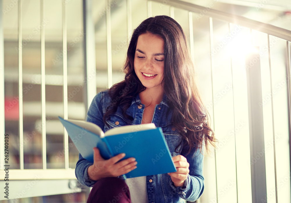 education, high school, university, learning and people concept - smiling student girl reading book at library education, high school, university, learning and people concept - smiling student girl reading book at library
