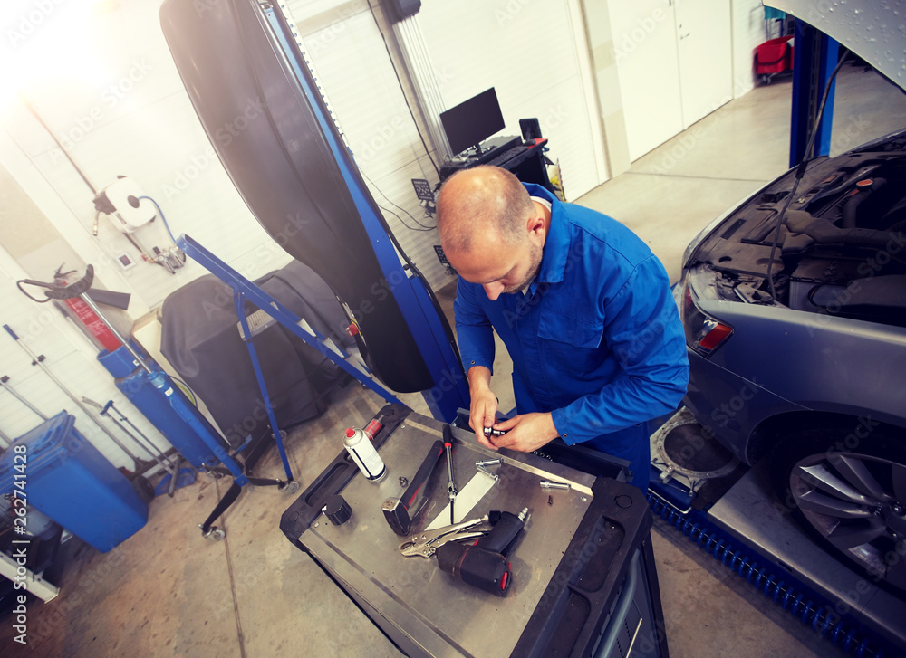 car service, repair, maintenance and people concept - auto mechanic man with wrench and lamp working at workshop car service, repair, maintenance and people concept - auto mechanic man with wrench and lamp working at workshop